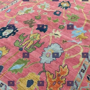 Pink Oushak rug hand knotted from fine quality wool with a beautiful soft pink background and intricate multicolor floral and vine patterns.