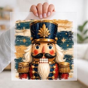 May include: A square print featuring a nutcracker with a blue hat adorned with a gold leaf emblem, a black mustache, white hair and beard, and a red uniform with gold epaulets. The background is a textured blue and gold starry night sky.