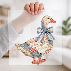 May include: A decorative goose cutout made of various fabric patches, including floral, blue denim, and red-and-white gingham patterns. The goose features a prominent blue-and-white checkered bow around its neck and a red-and-white gingham beak and feet.