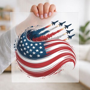 May include: A square transparent sheet featuring a graphic illustration of the American flag swirling into a circular motion. Five dark blue fighter jets are flying in formation, leaving behind red, white, and blue smoke trails that blend into the flag.