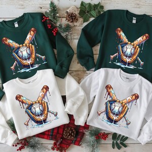 May include: Four crewneck sweatshirts, two in dark green and two in white. Each sweatshirt features a baseball design with a baseball, bat, and glove with dripping details. The design is in shades of blue, brown, and white.