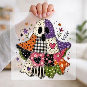 May include: A ghost-shaped graphic design featuring a patchwork quilt pattern with various fabrics in orange, purple, pink, green, black, and white. The design includes heart shapes, floral prints, stars, and plaid patterns with visible black stitching.