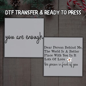 May include: Two white square DTF transfers with black text. One says "you are enough" in cursive. The other says "Dear Person Behind Me, The World Is A Better Place With You In It Lots Of Love the person in front of you."