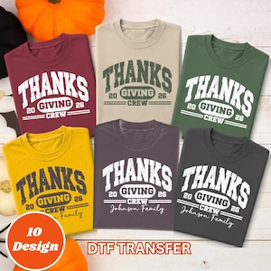 May include: Six crewneck t-shirts in maroon, beige, green, yellow, dark purple, and charcoal gray. Each shirt features a distressed white or dark graphic with the text THANKS GIVING CREW 20 26. Some shirts include the text Johnson Family.