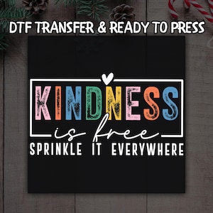 May include: A black square with the words "KINDNESS is free, sprinkle it everywhere" in a colorful, whimsical font. The words are inside a white rectangular border. The phrase "DTF TRANSFER & READY TO PRESS" is at the top.