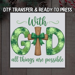 May include: A square DTF transfer with the text "DTF TRANSFER & READY TO PRESS". The design features the words "With God" with the letters "G" and "D" filled with shamrocks. A wooden cross with a green bow is in the center, and the phrase "all things are possible" is at the bottom.