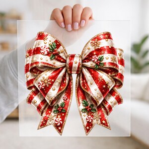 May include: A decorative bow featuring alternating red and white glittery stripes, adorned with gold star accents, small peppermint candies, and green holly leaves with red berries. The bow has a structured shape with two main loops and two tails.