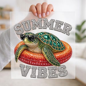 May include: A decorative image featuring a bejeweled sea turtle wearing sunglasses, resting on a sparkling orange float. The words "SUMMER VIBES" are displayed above and below the turtle in a sparkling font. The image is held up by a person.