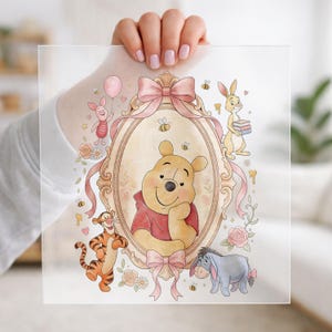 May include: A clear, square print featuring a watercolor illustration of Winnie the Pooh and friends. The central image is of Pooh Bear in a red shirt, surrounded by characters like Piglet, Tigger, Eeyore, and Rabbit, with pink bows and floral accents.