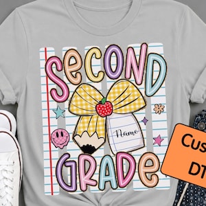 Peut inclure: Un t-shirt gris clair avec un motif imprimé affichant le texte SECOND GRADE en lettres bulles colorées. Le design comprend un nœud à carreaux jaunes, un crayon, une pomme rouge et une page de cahier avec le mot Name. Un panneau orange indique Custom DTF.