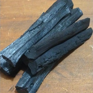 May include: A pile of black charcoal sticks, likely for grilling or smoking.