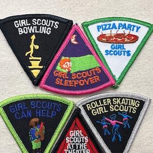 May include: A collection of six Girl Scout patches in various colors and designs. The patches feature text such as "Girl Scouts Bowling," "Pizza Party," and "Roller Skating Girl Scouts." Each patch has a unique illustration related to the activity.