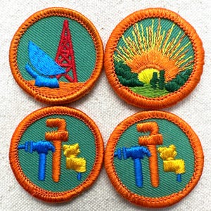 May include: Four embroidered patches with orange borders and green centers. Designs include a blue satellite dish and red tower, a sunrise over green trees, and tools in blue and orange with a yellow cat-like figure. Patches are round.