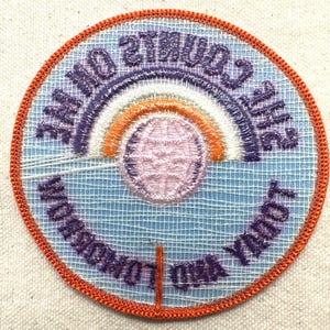K&ouml;nnte beinhalten: Gestickter Aufn&auml;her mit hellblauem Hintergrund, mit einem Regenbogen und einem Globus-Design. Der Aufn&auml;her tr&auml;gt die Aufschrift "World London Youth" und "Counts 2012". Der Rand ist orange.
