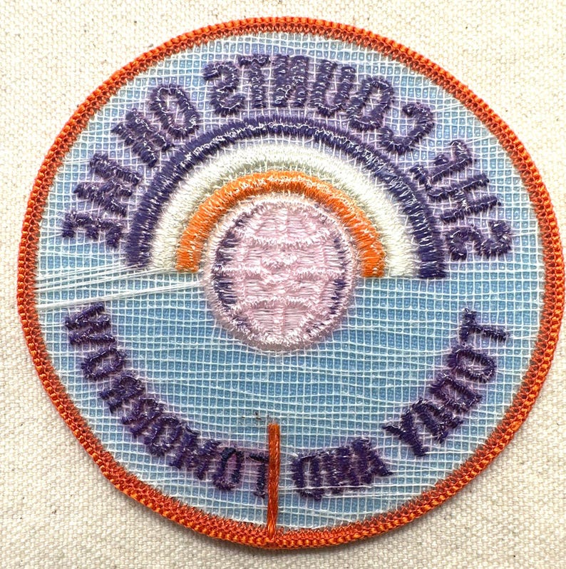 K&ouml;nnte beinhalten: Gestickter Aufn&auml;her mit hellblauem Hintergrund, mit einem Regenbogen und einem Globus-Design. Der Aufn&auml;her tr&auml;gt die Aufschrift "World London Youth" und "Counts 2012". Der Rand ist orange.