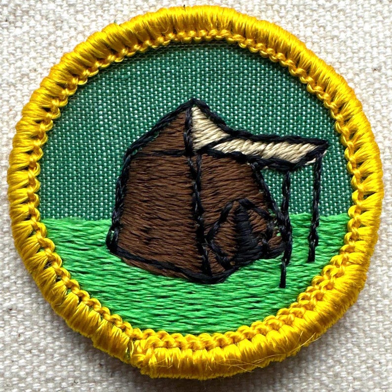 Pu&ograve; includere: Toppa ricamata rotonda raffigurante una tenda marrone con tetto beige, su sfondo verde. La toppa ha un bordo cucito giallo. Ideale per gli appassionati di campeggio o attivit&agrave; all'aperto.