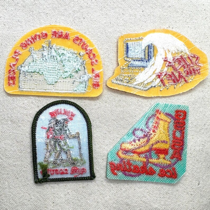 May include: Four embroidered patches with various designs. One yellow patch features a building and text. Another yellow patch shows a computer and a wave. A green and white patch depicts hikers. A teal patch displays a roller skate.