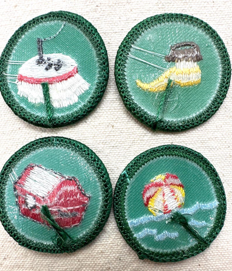 May include: Four round green embroidered patches with various designs. One patch features a white and red umbrella, another a yellow and brown object, a red structure, and a beach ball in water. Each patch has a green border.