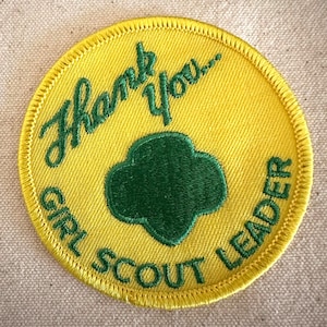 May include: Yellow Girl Scout Leader patch with green embroidered text and a green trefoil emblem. The patch reads "Thank You..." and "GIRL SCOUT LEADER" in green script and block letters.