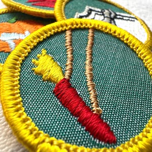 May include: Embroidered patches with yellow borders and green fabric. One patch features a red and yellow carrot design with tan strings. Other patches show a pumpkin, a red design, and a white design.