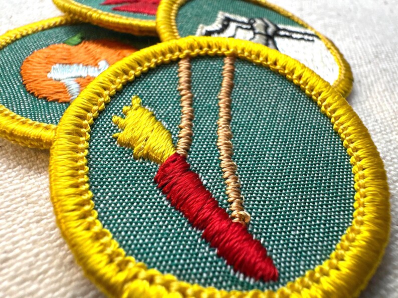May include: Embroidered patches with yellow borders and green fabric. One patch features a red and yellow carrot design with tan strings. Other patches show a pumpkin, a red design, and a white design.