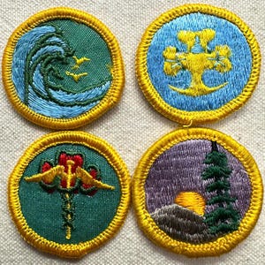 May include: Four circular embroidered patches with yellow borders. The top left features a blue wave on green. The top right shows a yellow emblem on blue. The bottom left displays a yellow caduceus on green. The bottom right depicts a sunset.