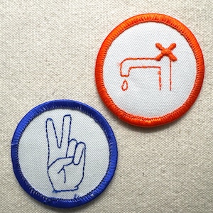 May include: Two embroidered patches. One features a blue hand making a peace sign, the other an orange faucet with a dripping water drop. Both are circular with a white center and a colored border.