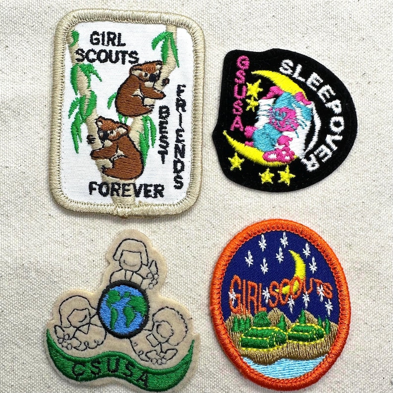 K&ouml;nnte beinhalten: Vier Pfadfinder-Abzeichen. Ein rechteckiges Abzeichen zeigt Koalas auf einem Baum mit dem Text "Girl Scouts Best Friends Forever". Ein weiteres Abzeichen ist schwarz mit einem Mond und dem Wort "Sleepover". Zwei weitere Abzeichen sind ebenfalls enthalten.