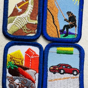 May include: Four embroidered patches with blue borders. One depicts a dinosaur skeleton with tools, another a person climbing a rock face, a third shows a cart with produce, and the last a red car.