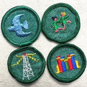 May include: Four round green embroidered patches. One features a blue bird in flight, another shows two figures dancing, a third depicts a radio tower with yellow lightning bolts, and the last has colorful abstract shapes.