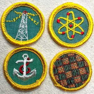 May include: Four embroidered patches with yellow borders. Designs include a white radio tower, a yellow atom with red dots, a white and red anchor, and a green and orange woven pattern, all on a teal background.