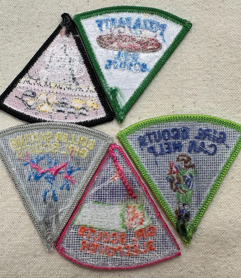 Puede incluir: Una colecci&oacute;n de cinco parches triangulares bordados con varios dise&ntilde;os y texto. Los parches presentan diferentes colores, incluyendo verde, rosa y azul, con fondos blancos y grises. El texto en los parches est&aacute; en varias fuentes y colores.