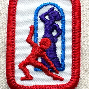 Puede incluir: Parche bordado con borde rojo y centro blanco. El dise&ntilde;o presenta dos figuras estilizadas: una figura roja en movimiento y una figura morada dentro de un arco azul. El parche es probablemente para ropa o accesorios.
