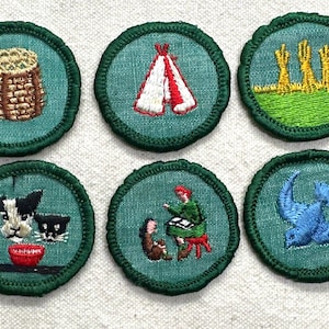May include: Six embroidered patches with green borders and teal centers. The patches depict a woven basket, a teepee, wheat stalks, a dog and cat with a bowl, a person with animals, and a blue bird.