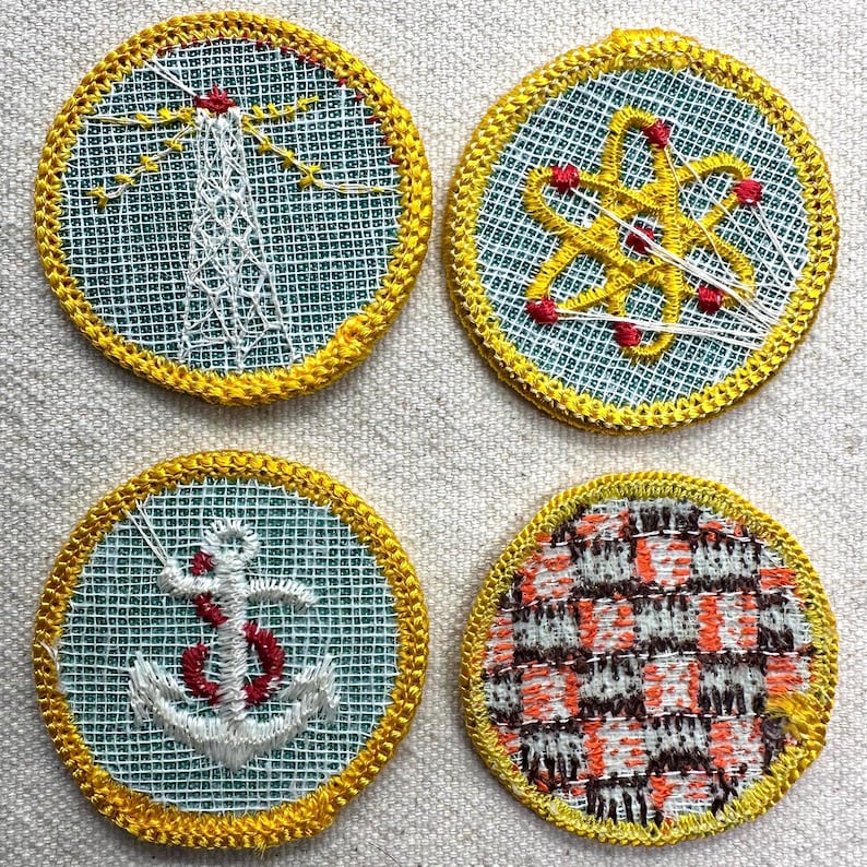 May include: Four circular embroidered patches with yellow edging. Designs include a lighthouse, an atom, an anchor, and a plaid pattern. The patches are stitched on a light blue mesh background.