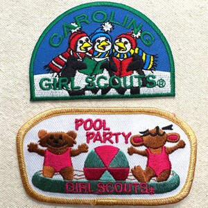 May include: Two Girl Scout patches. The top patch is blue with penguins wearing hats and scarves, and the text "CAROLINA GIRL SCOUTS". The bottom patch has a pool party theme with bears in swimsuits and the text "POOL PARTY GIRL SCOUTS".