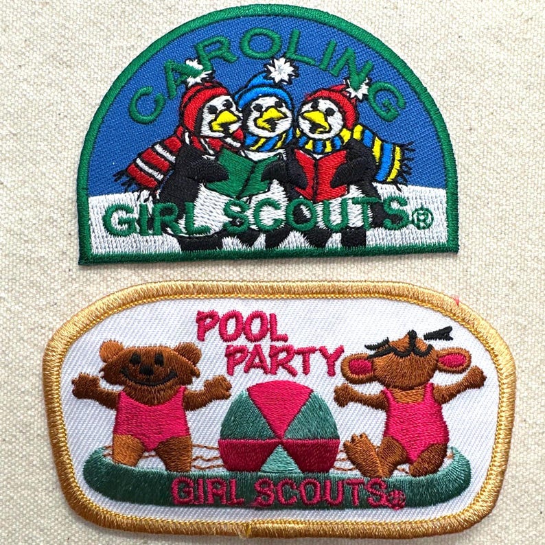 May include: Two Girl Scout patches. The top patch is blue with penguins wearing hats and scarves, and the text "CAROLINA GIRL SCOUTS". The bottom patch has a pool party theme with bears in swimsuits and the text "POOL PARTY GIRL SCOUTS".
