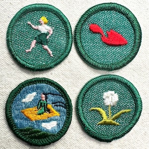 May include: Four embroidered patches with green borders and backgrounds. The patches feature various designs: a person running, a red shape, a person on a flying carpet, and a white flower.