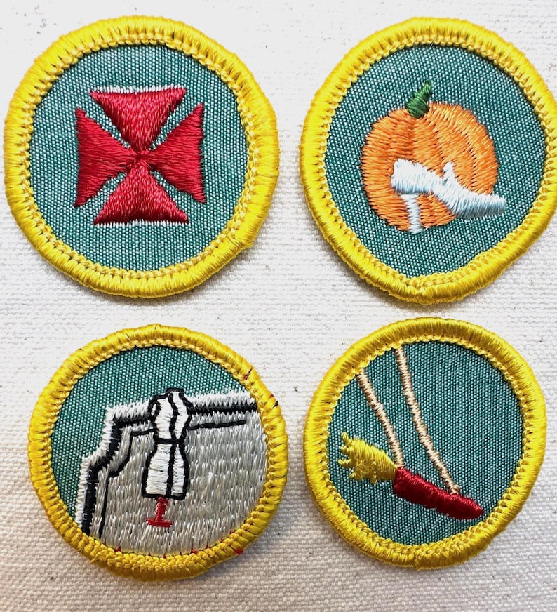 May include: Four embroidered patches with teal backgrounds and yellow borders. Designs include a red cross, an orange pumpkin with a white shoe, a sewing machine with a dress form, and a red swing with a yellow tassel.