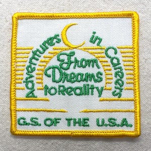 May include: Embroidered patch with a white background and a yellow border. The patch features the text "Adventures in Careers" and "From Dreams to Reality" in green, with a yellow crescent moon. The text "G.S. OF THE U.S.A." is also included.
