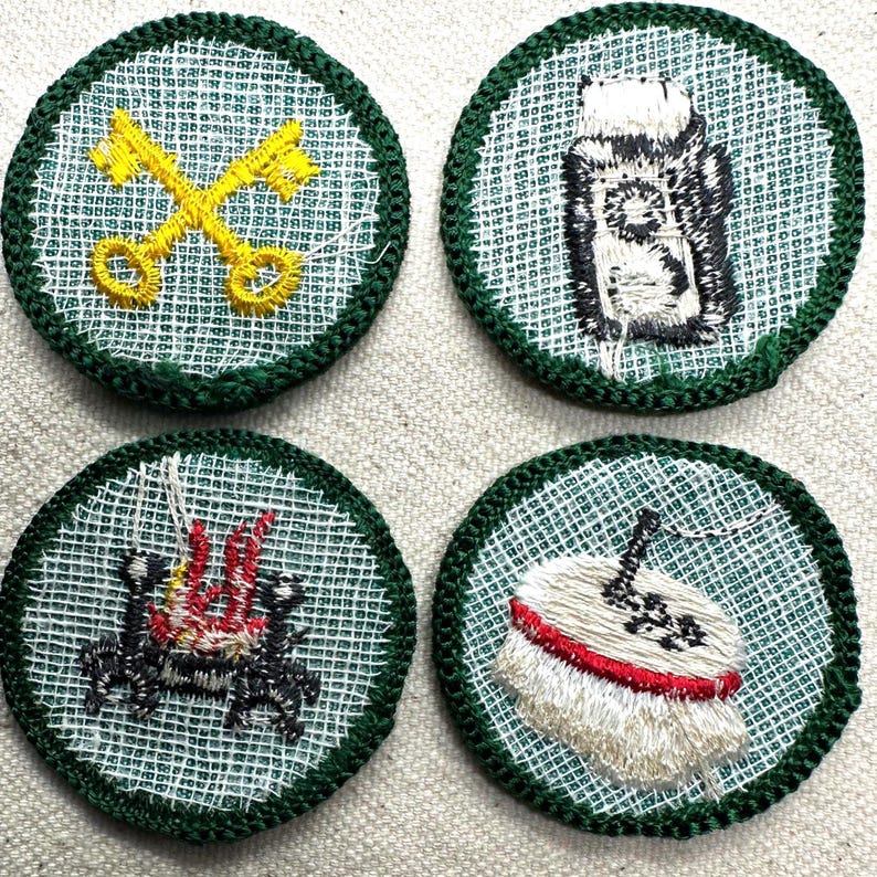 May include: Four embroidered patches with green borders. The patches feature various designs: crossed yellow keys, a black and white object, a red and black design, and a white object with a red band.