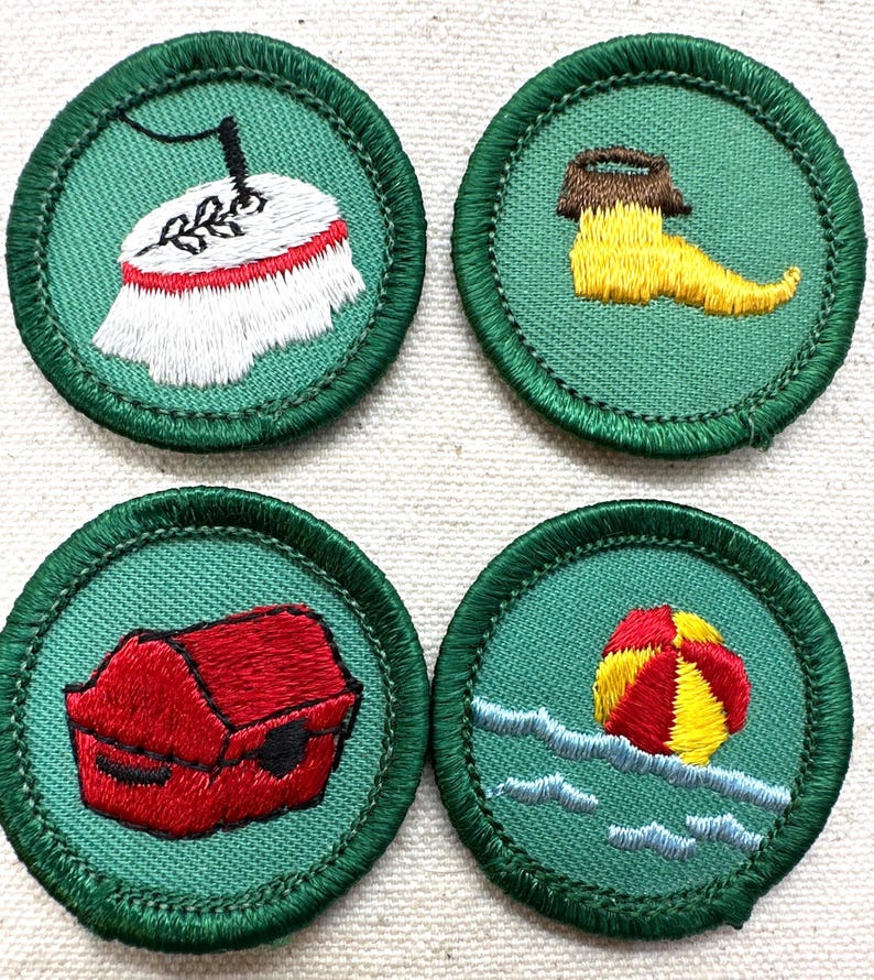 May include: Four embroidered patches with green borders. The patches feature various designs: a table with a white tablecloth, a yellow boot, a red chest, and a beach ball in the water. Each patch is circular and has a green background.