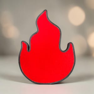 May include: A red flame-shaped object with a black outline. The object has a smooth, glossy surface and a stylized design. The flame shape is a common symbol for fire and heat.