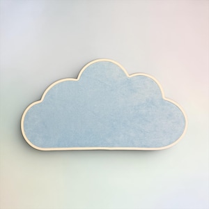 May include: A cloud-shaped wall decor piece featuring a textured, light blue surface with a smooth, light-colored wooden border outlining the entire shape. The object has a flat, horizontal base and a rounded, multi-lobed top edge.