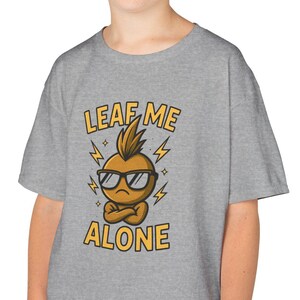 May include: A grey t-shirt with a cartoon onion character wearing sunglasses and crossed arms. The text "LEAF ME ALONE" is printed above and below the character in yellow. The shirt has short sleeves.
