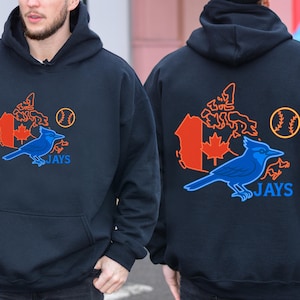 May include: Navy blue hooded sweatshirt with a blue bird graphic and the word "JAYS". The design includes a baseball and a map of Canada in orange and red. The sweatshirt has a hood and a front pocket.