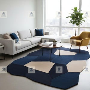 May include: A modern living room featuring a geometric area rug in shades of navy blue and beige. The rug's design complements the light gray sectional sofa, round coffee table, and mustard yellow armchair. A large window offers a view.