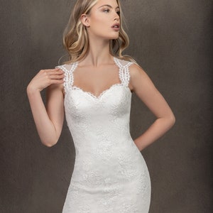 Puede incluir: Un vestido de novia de encaje blanco con escote de coraz&oacute;n y silueta ajustada. El vestido tiene una superposici&oacute;n de encaje con motivos florales y un dobladillo festoneado.