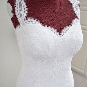 Puede incluir: Un vestido de novia de encaje blanco con escote de coraz&oacute;n y silueta ajustada. El vestido est&aacute; en un maniqu&iacute;.