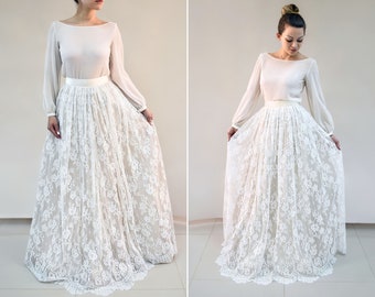 May include: A white lace skirt with a satin waistband. The skirt is floor-length and has a flowing silhouette.